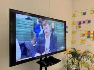 Tom select committee A photo of a TV screen in the PD office, showing Tom Loosemore giving evidence to the House of Commons Science and Technology Select Committee on 27 Nov 2018